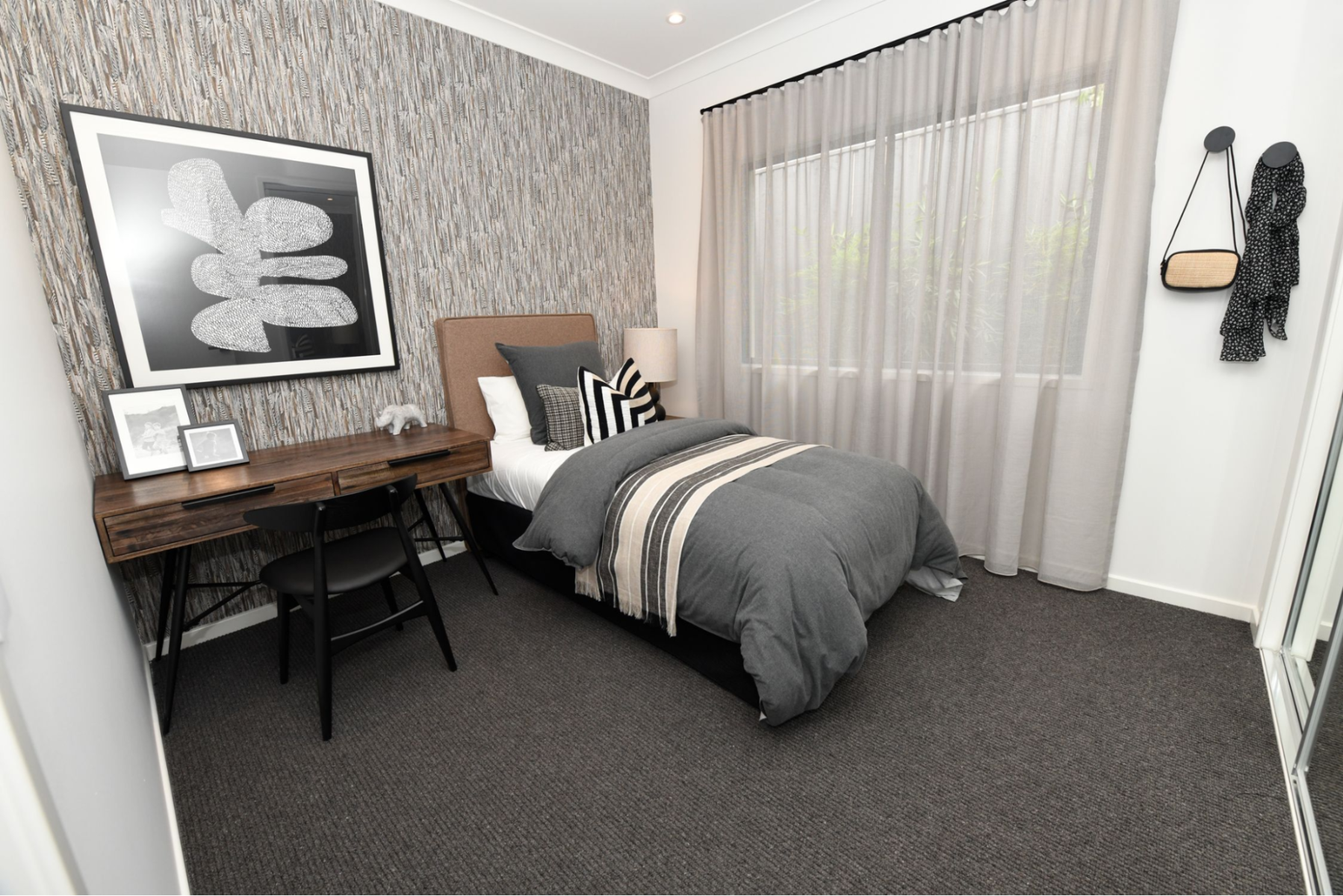 Small bedroom with grey carpets, a single bed in the corner, white walls and grey wallpaper
