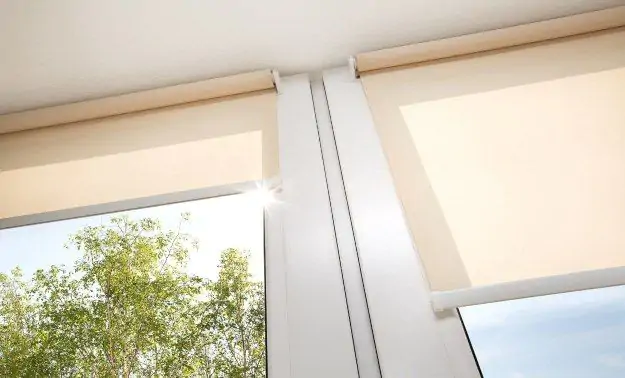 Roller blinds slightly covering two windows that are adjacent to each other