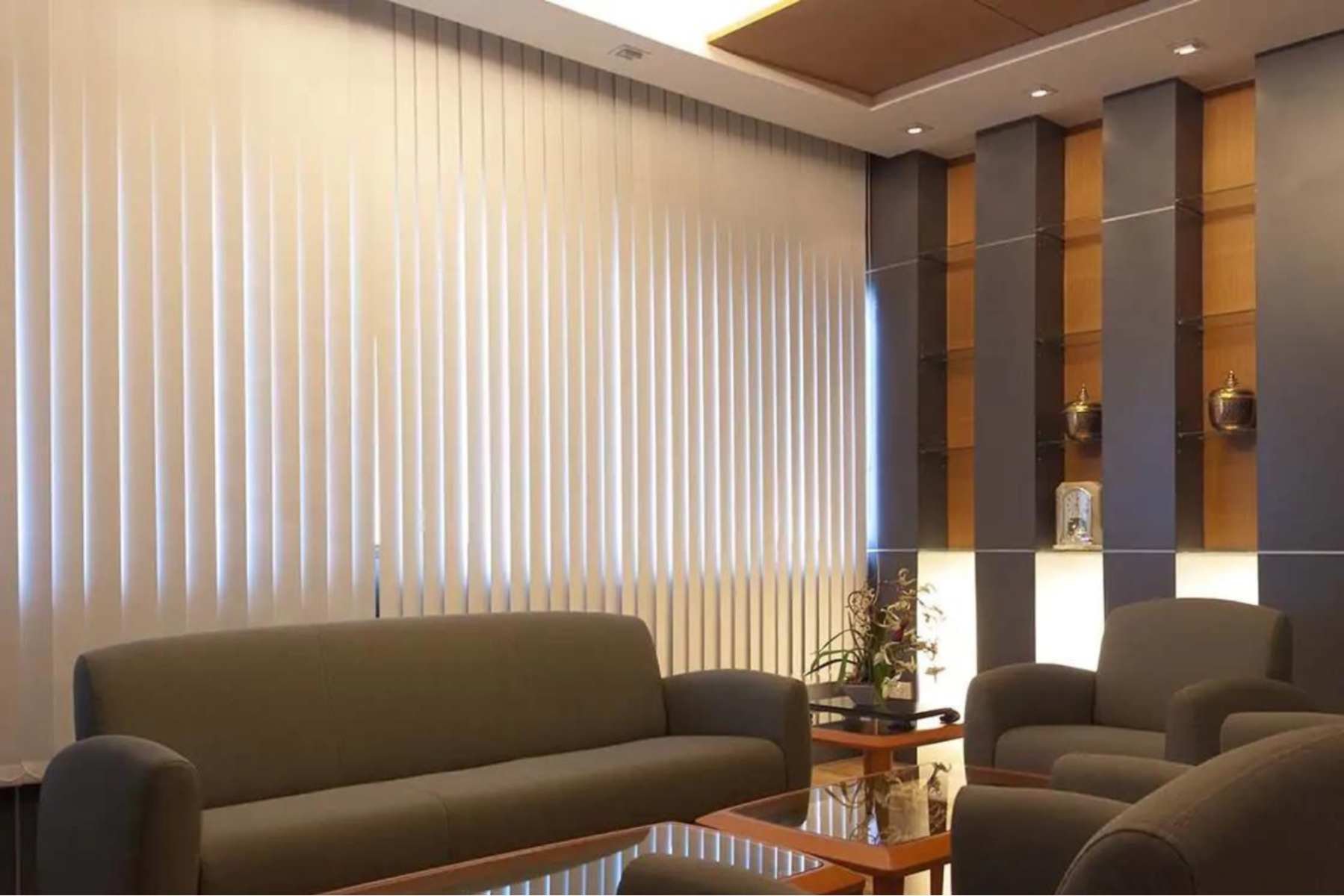Living area decorated with brown furniture and vertical blinds covering the window behind the sofa