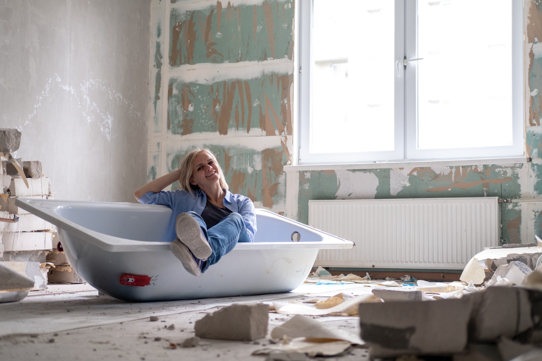Women sitting inside a bathtub in an under-renovation bathroom.